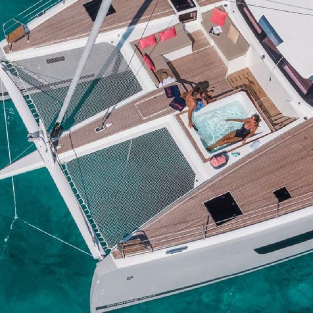 A couple enjoys a relaxing jacuzzi experience aboard a catamaran in the stunning waters of the Bahamas, surrounded by tropical beauty.